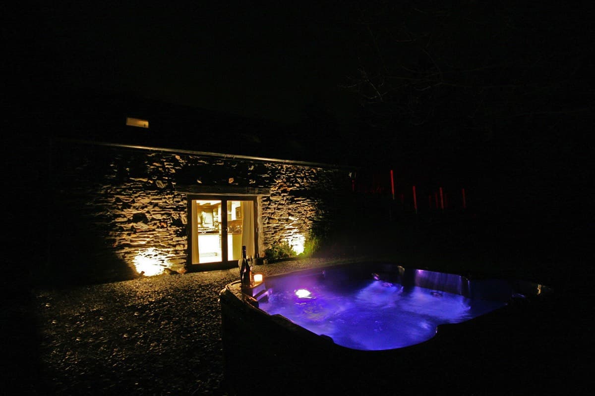 A hot tub at Sunridge Lodge in Devon, UK, lit up at night